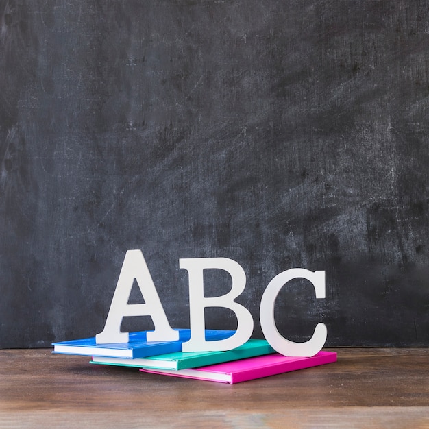 Table with alphabet letters on books near blackboard