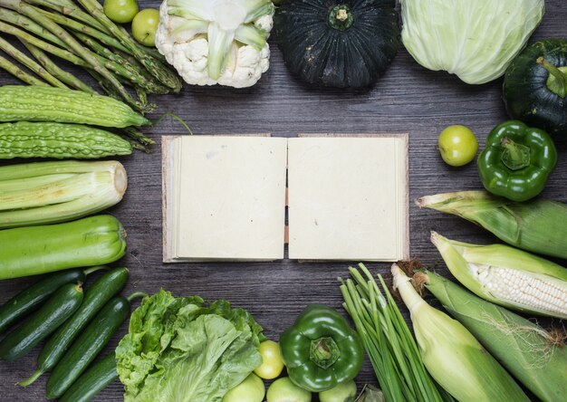 Table with green vegetables and an old book