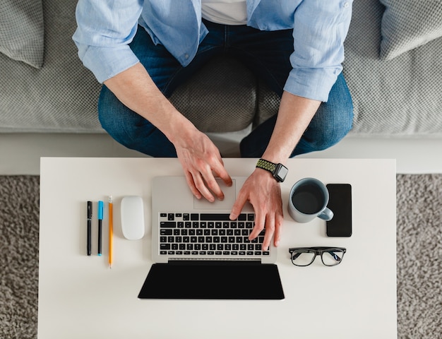 table workplace close-up man hands at home working typing on laptop