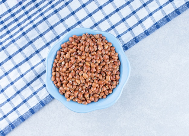 Tablecloth laid out underneath a small bowl of red beans on marble surface