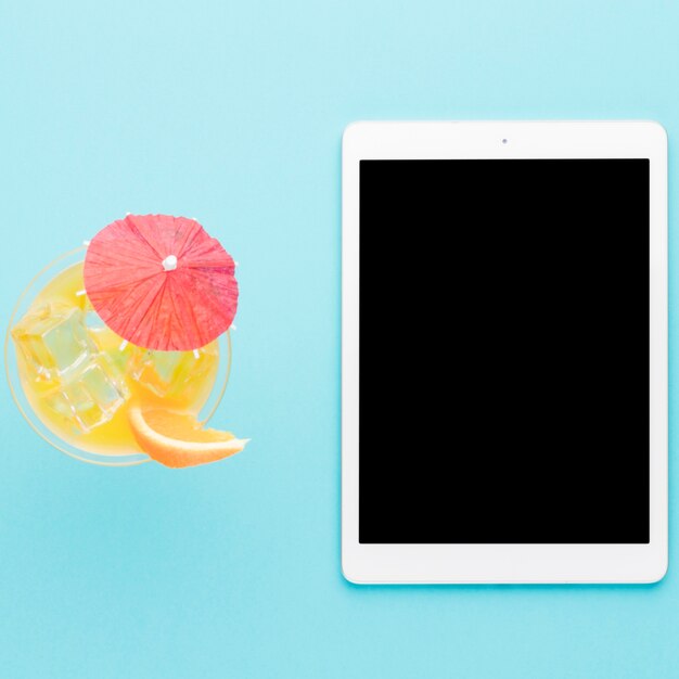 Tablet and cool cocktail on light background