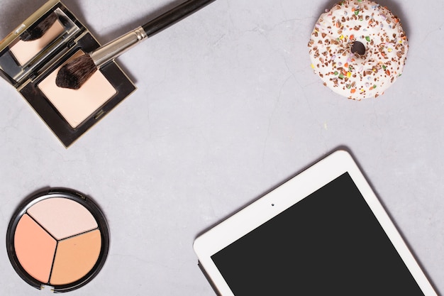 Free photo tablet and donut near face powder