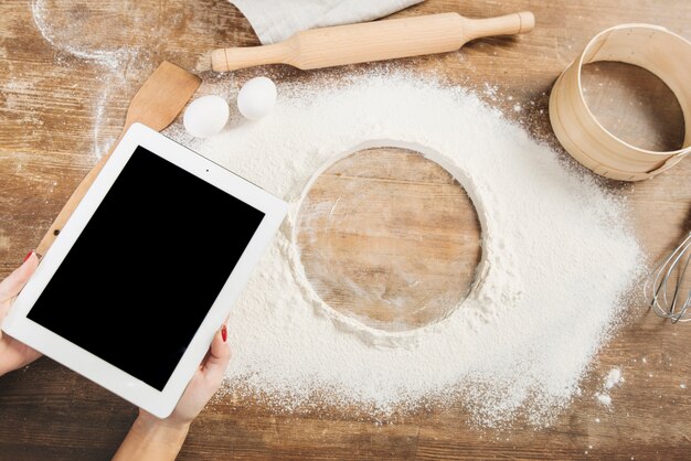Tablet and flour on wooden surface