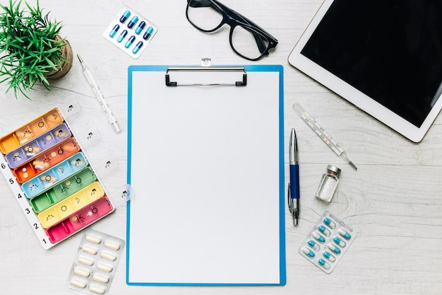 Tablet and medications around clipboard