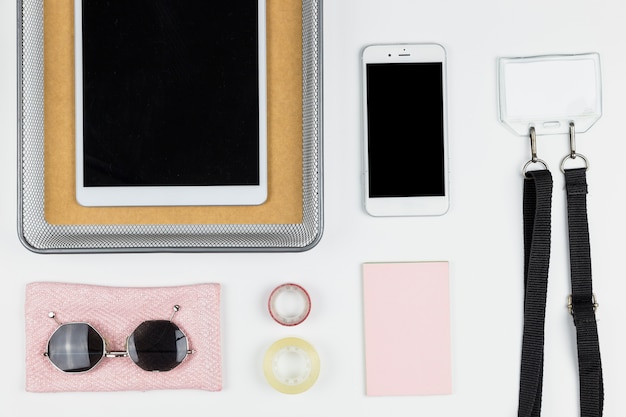 Tablet near smartphone, sunglasses, paper and name tag