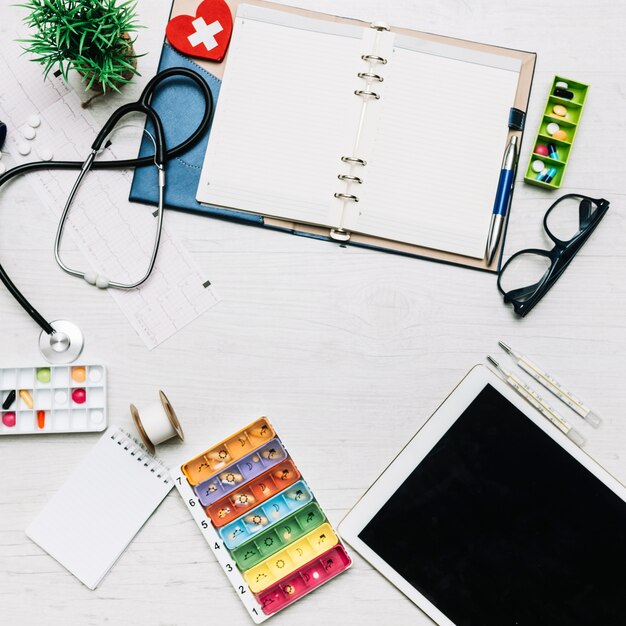 Tablet and notebook near medical supplies