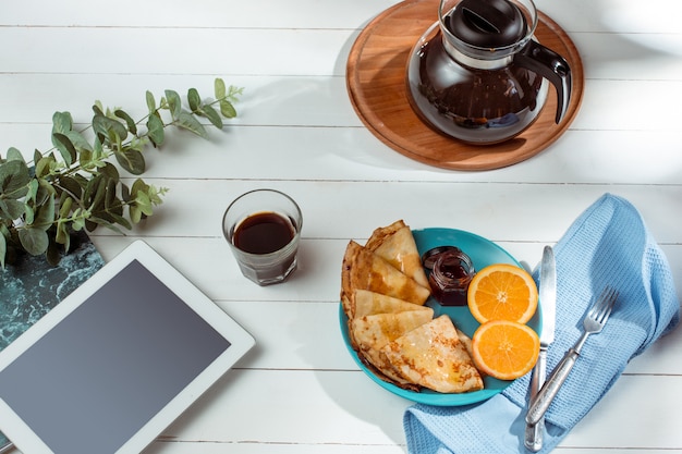 The tablet and pancakes with juice. Healthy breakfast