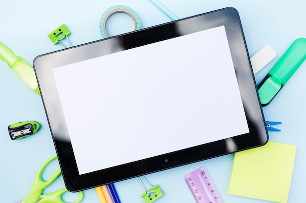 Tablet on stationery on blue background 