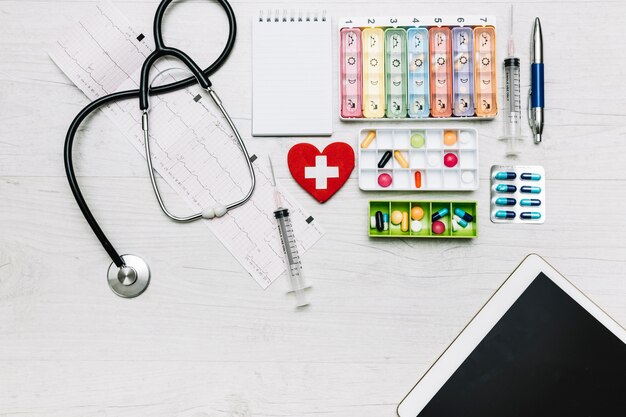 Tablet and stethoscope near pills organizers