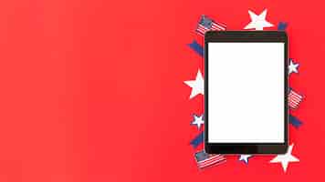 Free photo tablet with decorative elements of american flag on red surface