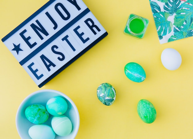 Tablet con godetevi il titolo di Pasqua vicino a uova nella ciotola tra può con liquido di tintura e tovagliolo