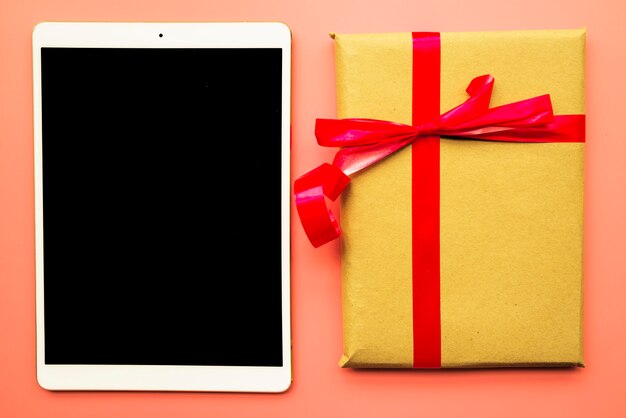 Tablet with gift box on table 