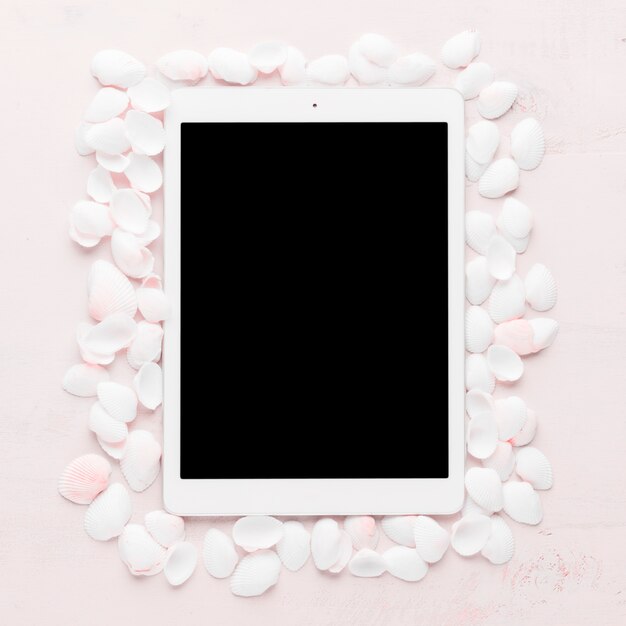Tablet with shells on light background