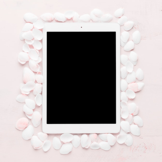 Tablet with shells on light background