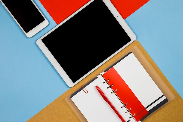 Tablet with smartphone and notebook on bright table