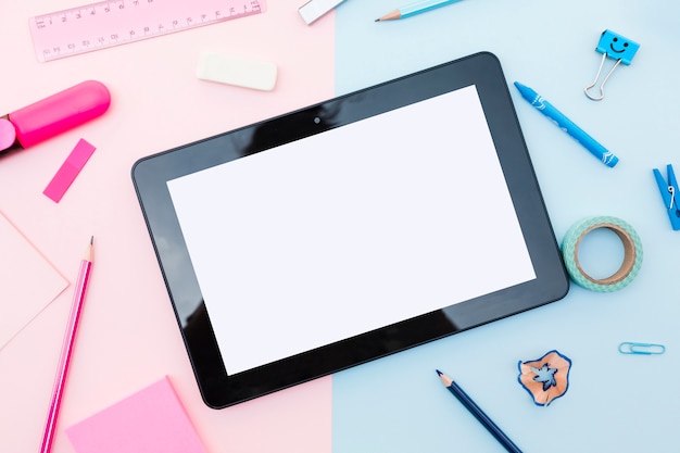 Tablet with stationery around on colorful background 