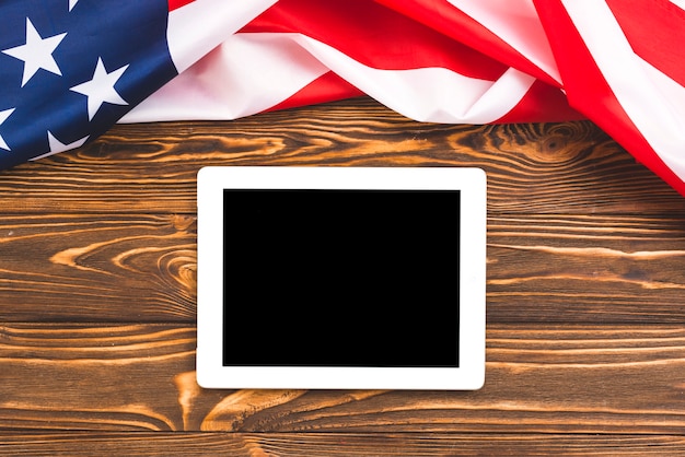 Tablet on wooden background with USA flag