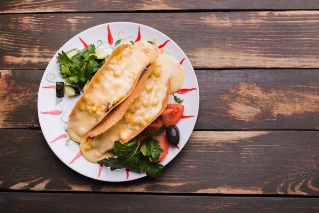 Tacos with sauce among vegetables on dish