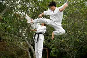 Foto gratuita allenamento di taekwondo che si svolge all'aperto nella natura con due persone