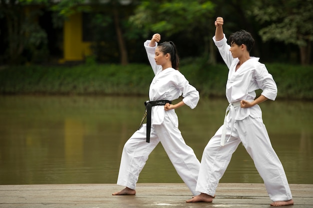 Foto gratuita allenamento di taekwondo che si svolge all'aperto nella natura con due persone