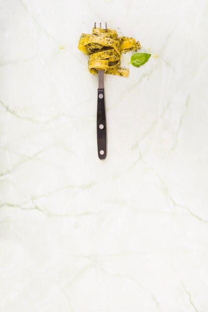 Tagliatelle pasta rolled on fork near green leaf