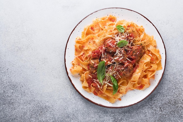 밝은 회색 슬레이트, 돌 또는 콘크리트 배경에 토마토 소스에 미트볼을 넣고 백리향을 넣은 탈리아텔레 파스타. 전통적인 이탈리아 요리와 요리. 복사 공간이 있는 상위 뷰입니다.