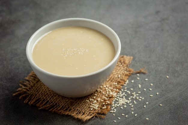 Tahini and sesame seeds on dark background