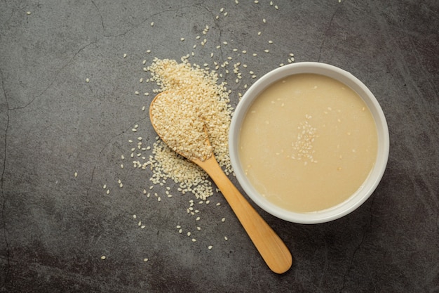 Tahini and sesame seeds on dark background