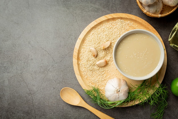 Tahini and sesame seeds on dark background