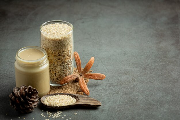 Tahini and sesame seeds on dark background