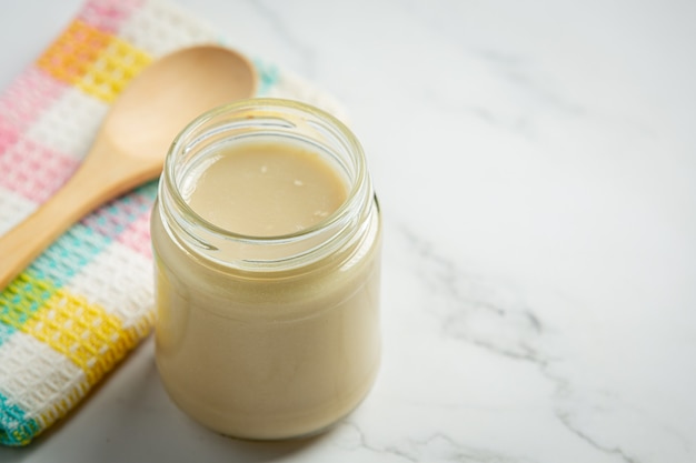 Tahini and sesame seeds on marble background