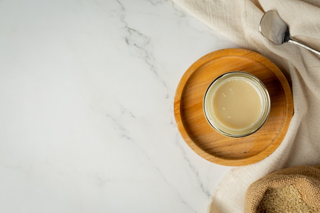 Tahini and sesame seeds on marble background