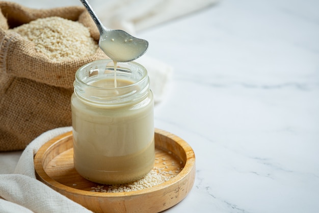 Tahini and sesame seeds on marble background