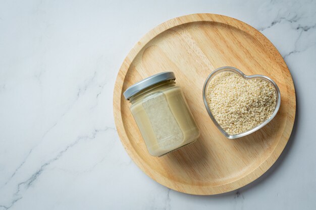 Tahini and sesame seeds on marble background