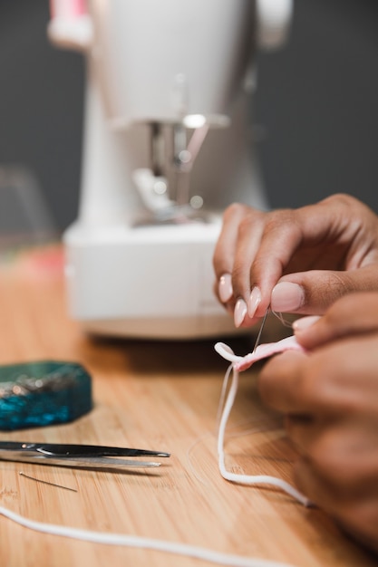 Tailor using a needle to make a fabric mask and blurred sewing machine