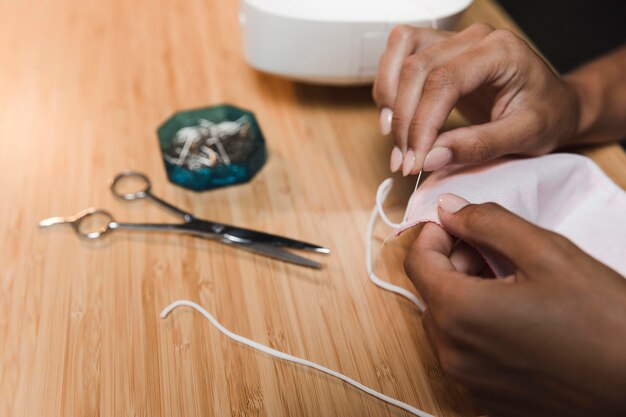 Tailor using a needle to make a fabric mask