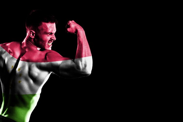 Tajikistan flag on handsome young muscular man black background