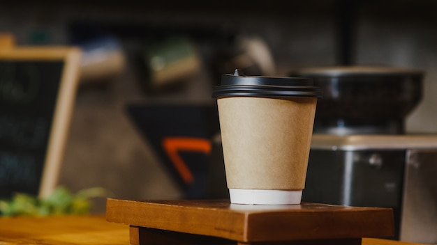 Free photo take away hot coffee paper cup to consumer standing behind bar counter at cafe restaurant.