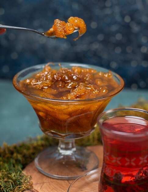 Free photo taking confiture with spoon along with a glass of tea