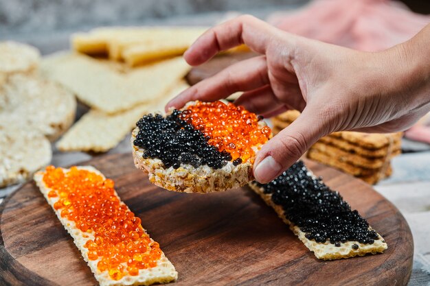 Taking a cracker sandwich with red and black caviar. 