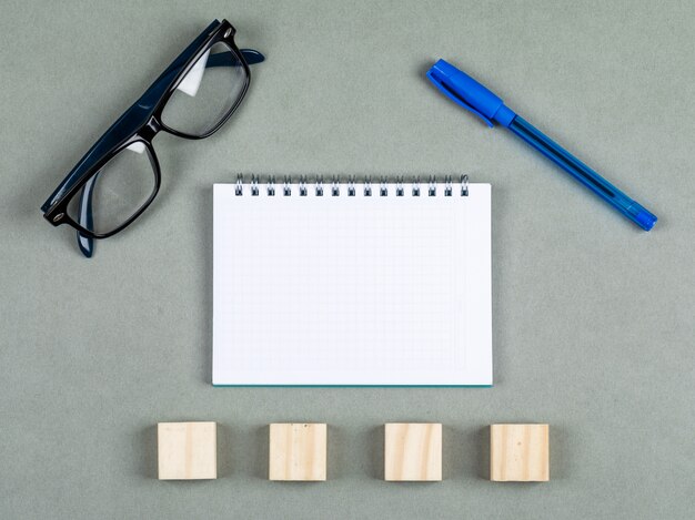 Taking notes concept with notebook, pen, eyeglasses, wooden elements on gray background top view. space for text. horizontal image