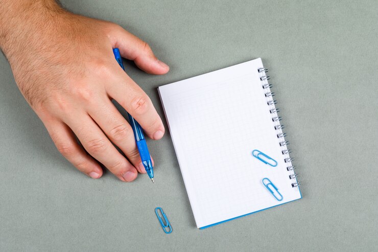 Free Photo taking notes and thinking concept with notebook on gray background top view. hand holds the pen. horizontal image