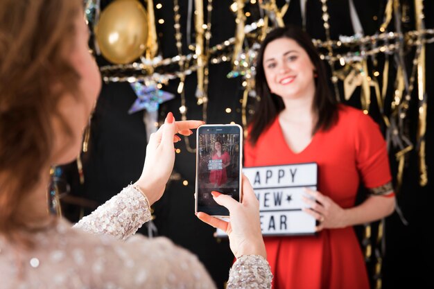 Taking photo of girl holding happy new year sign