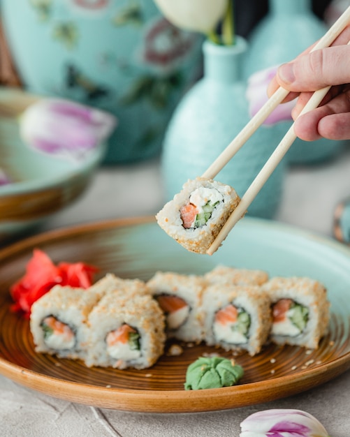 Taking sushi rolls with chopsticks.