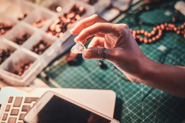 Free photo talented jewellery beads maker is holding crystal clear semi precious stone in hand.