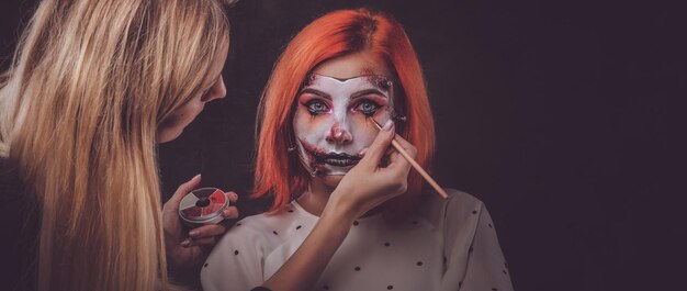 Talented makeup artist is creating special scary Halloween art on woman's face.