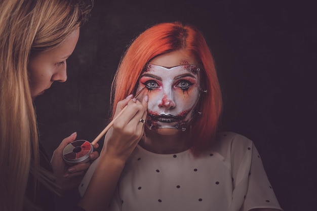 Talented makeup artist is creating special scary Halloween art on woman's face.