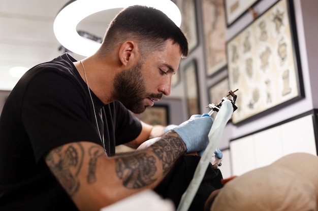 Talented tattoo artist doing his job side view