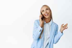 Бесплатное фото Разговорчивая милая деловая женщина разговаривает по мобильному телефону, улыбается и ведет счастливую беседу, стоя на белом фоне