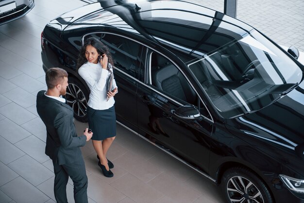 talking about that brand new vehicle. female customer and modern stylish bearded businessman in the automobile saloon